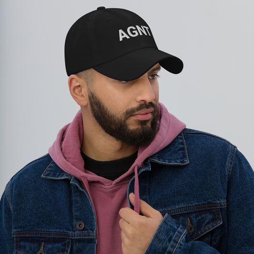 Man wearing a black cap with 'Top Pick' logo, denim jacket, and pink hoodie on a gray background